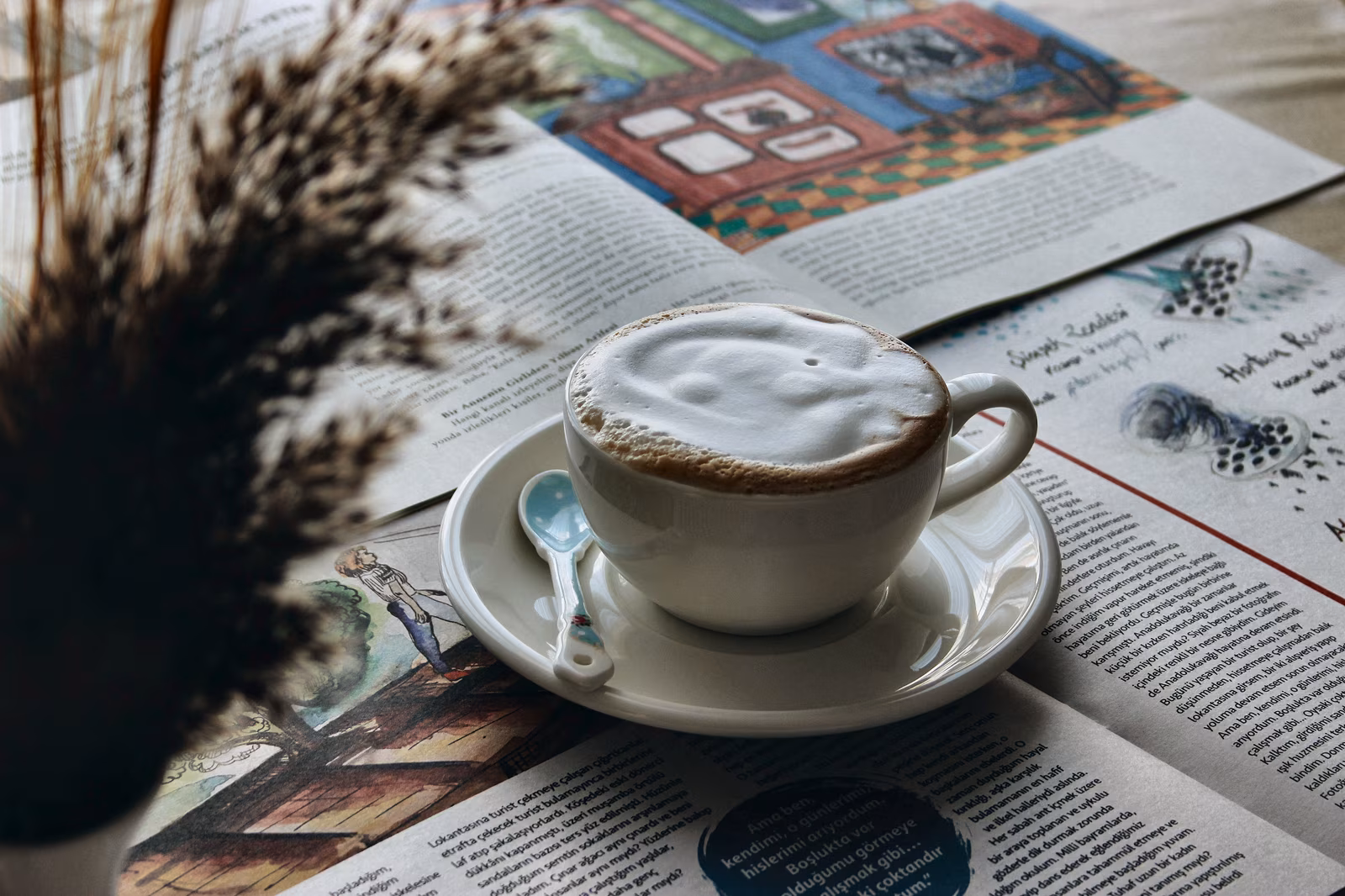 Een kop koffie naast kranten en tijdschriften.