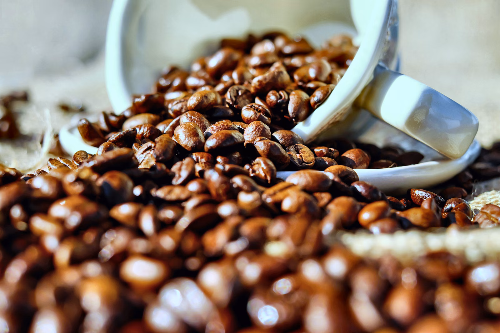 Gebrande koffiebonen vallen uit een kopje.