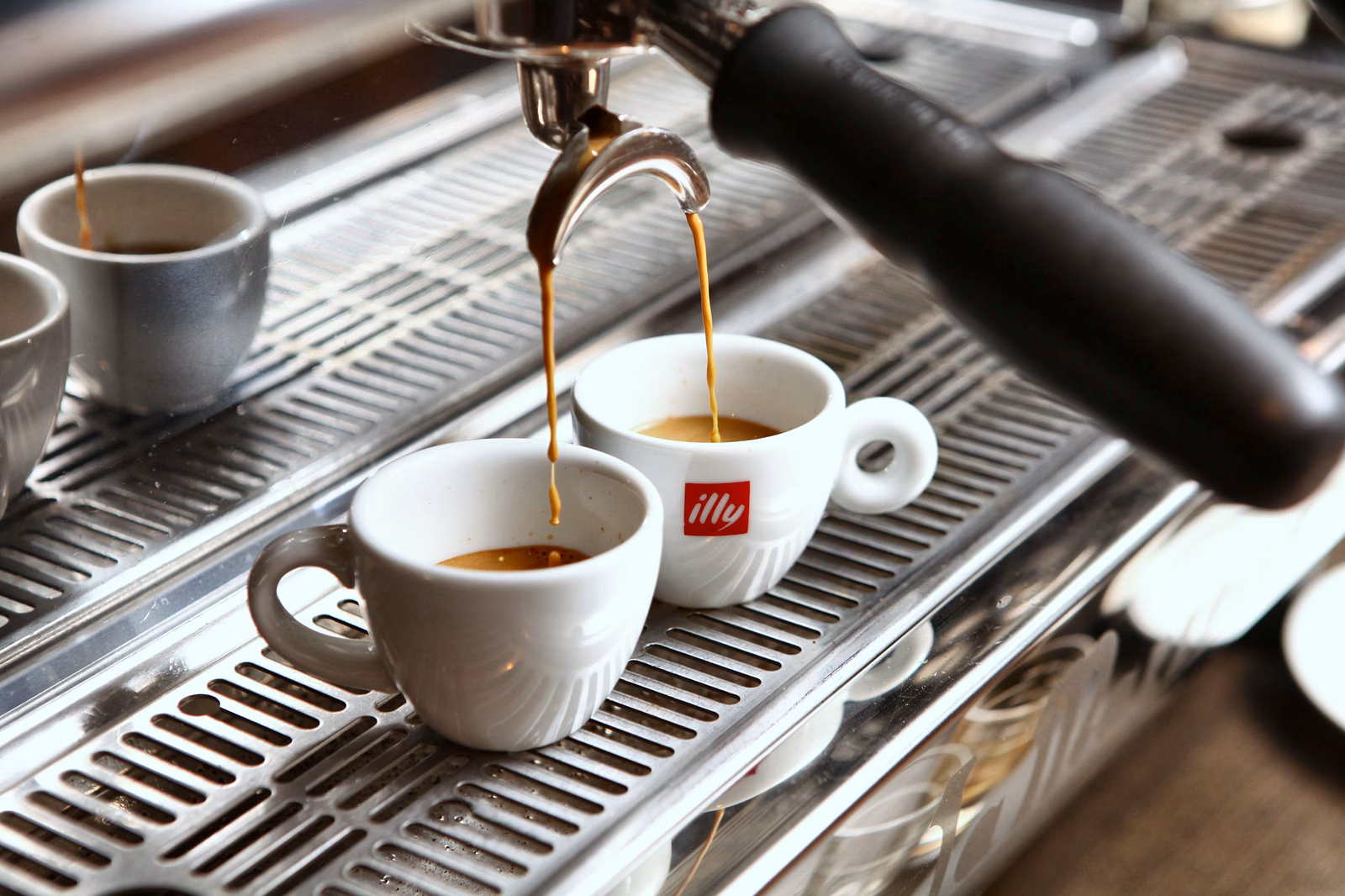 Espresso wordt in twee witte kopjes geschonken.