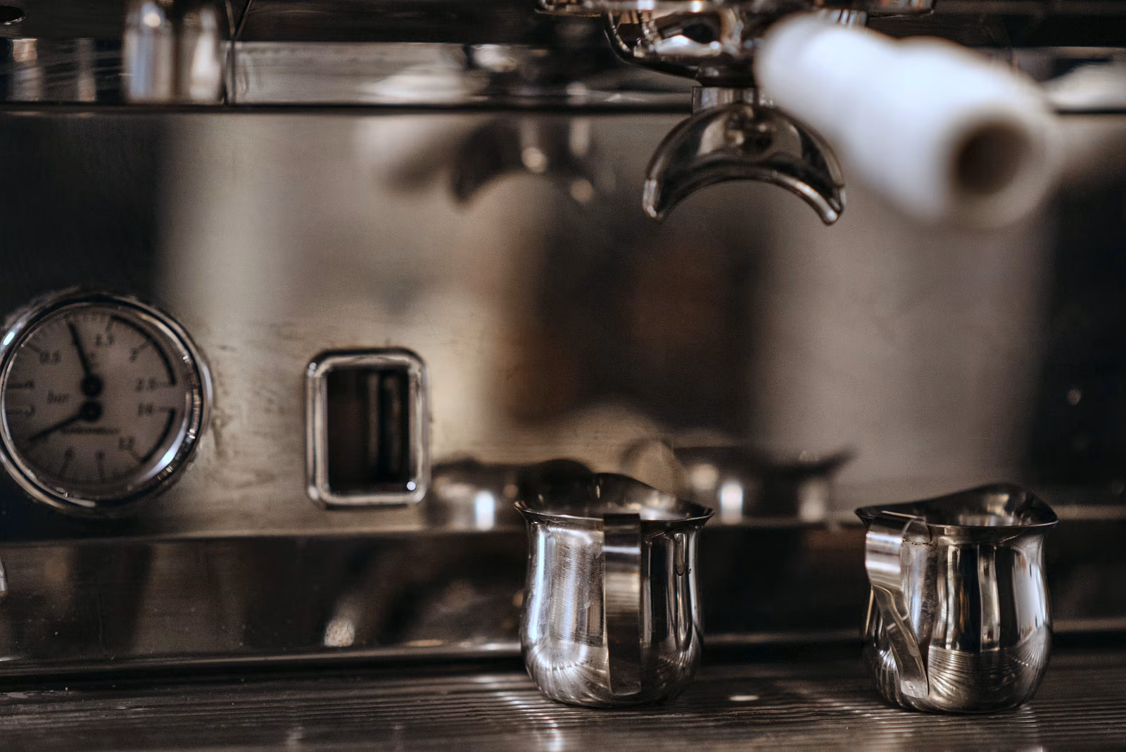 An espresso machine with a milk pitcher on the counter.