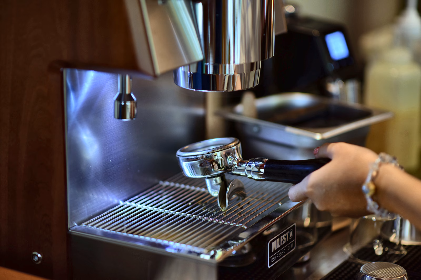 A hand operating a portafilter at an espresso machine.