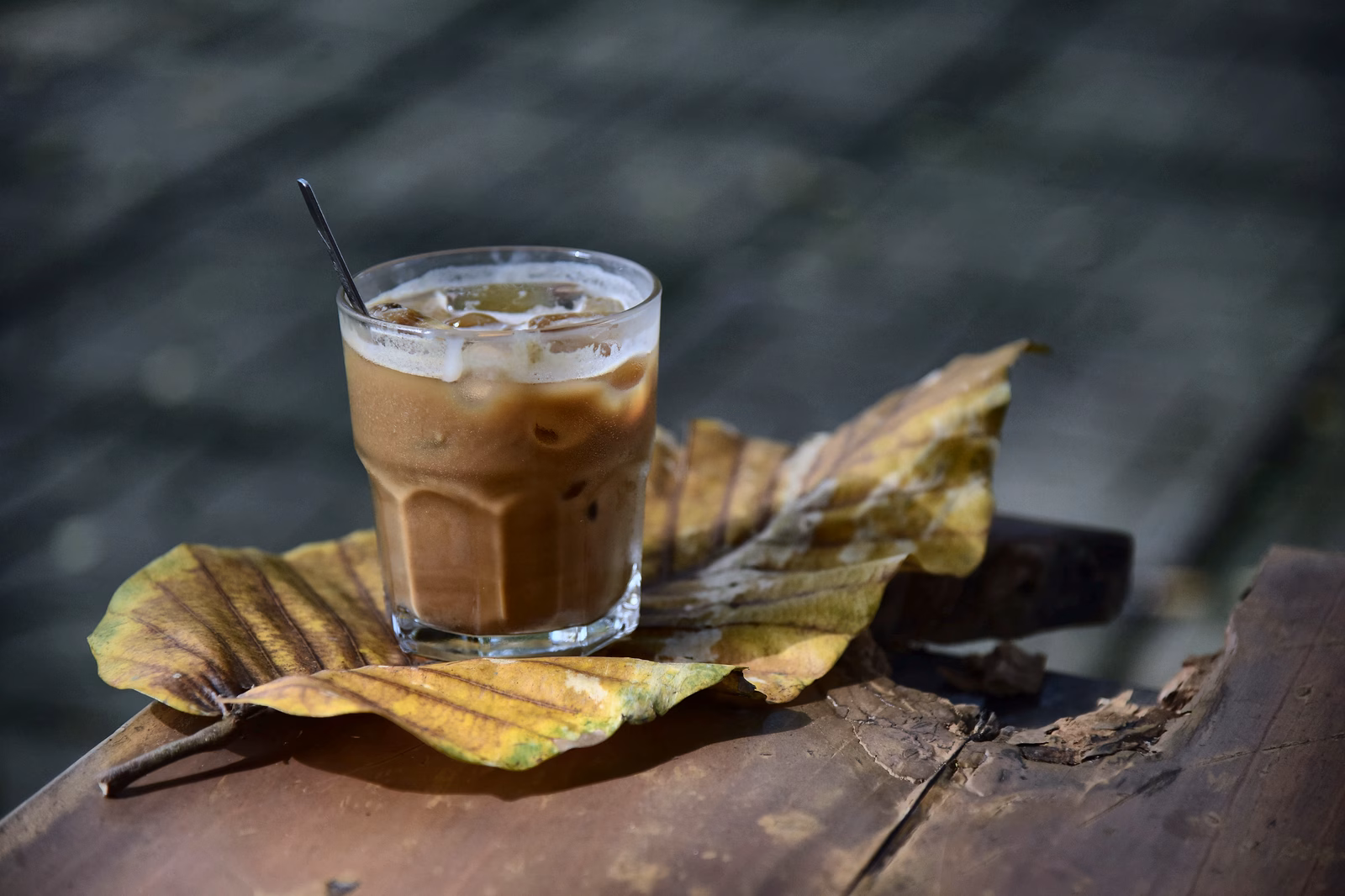 Een glas ijskoffie met een rietje op een houten oppervlak.