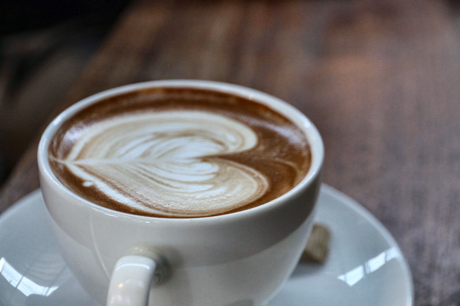 A white cup of coffee with a pattern in the milk foam.