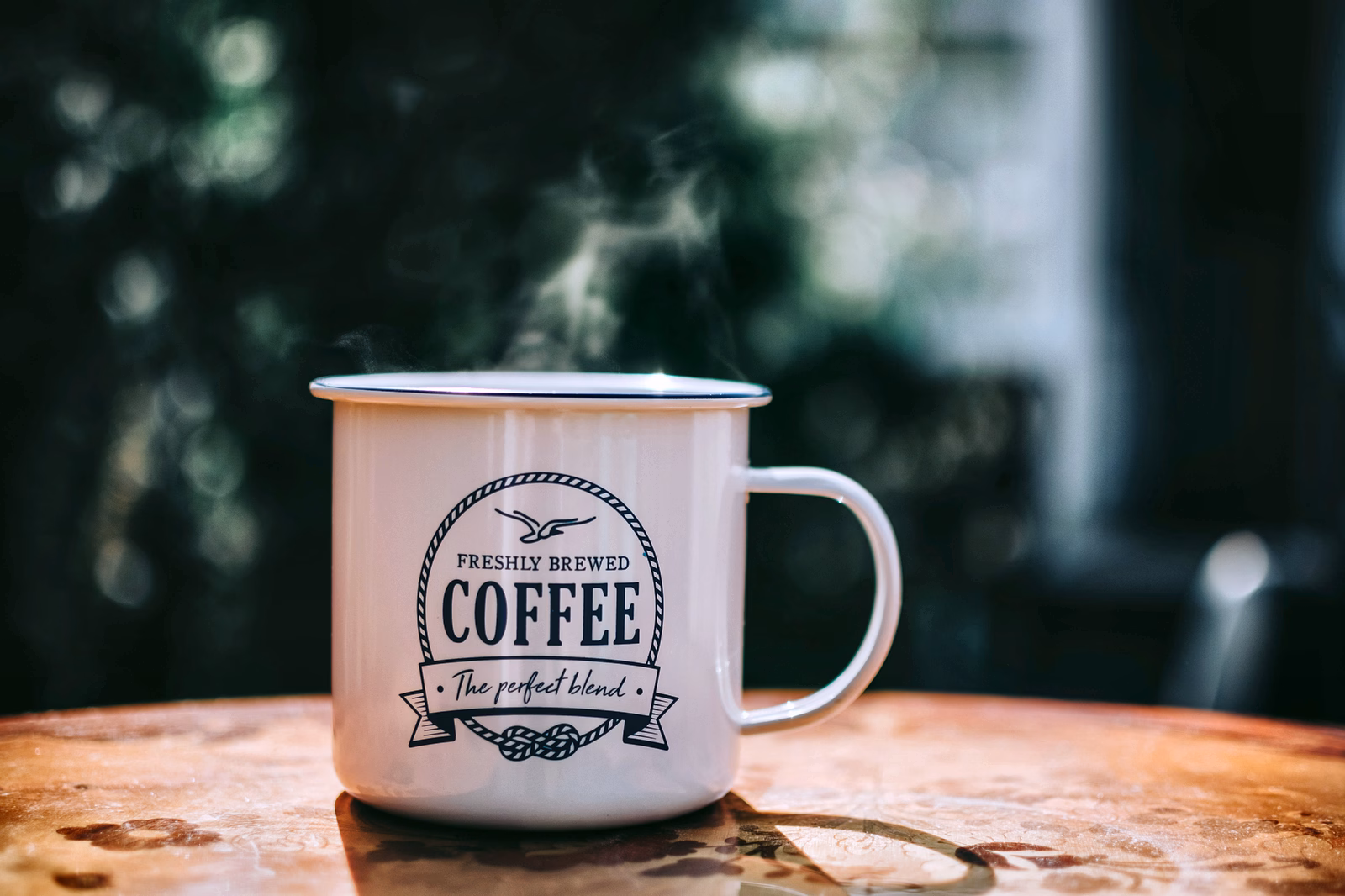 Een dampende mok koffie op een houten tafel.