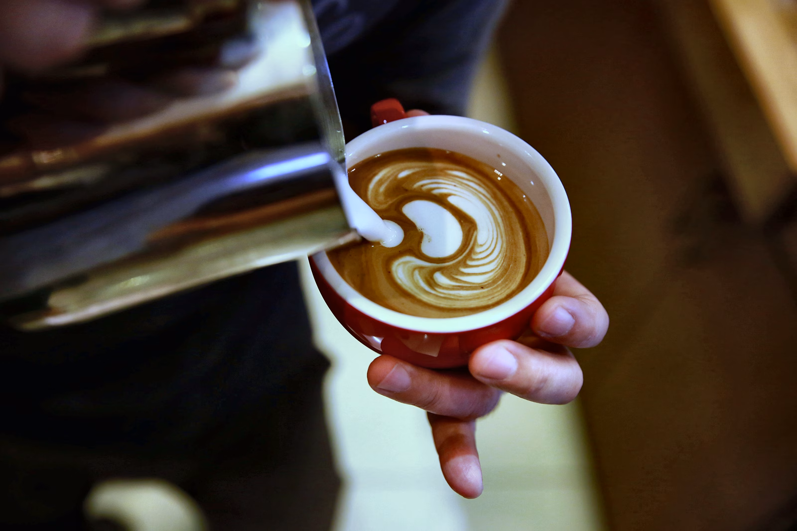 Milk being poured into coffee to create latte art.