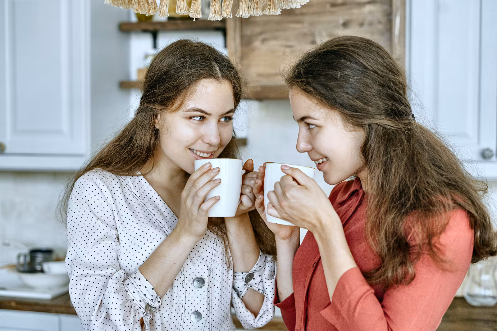 Twee vrouwen drinken samen koffie in een keuken.